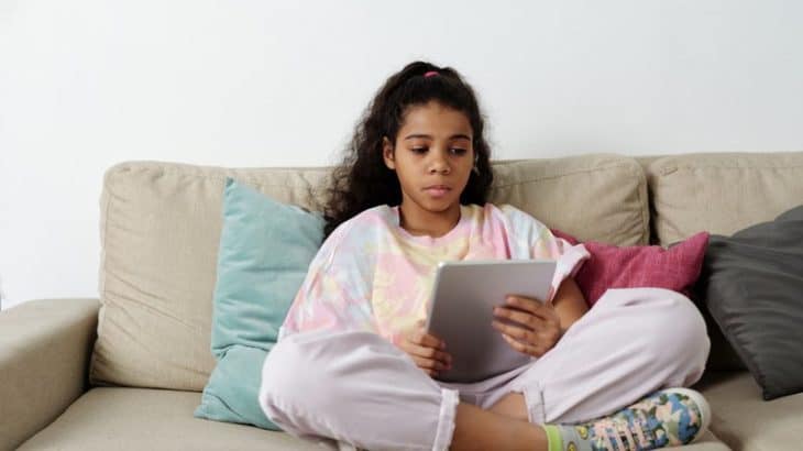 a tween girl reading a book on her kindle
