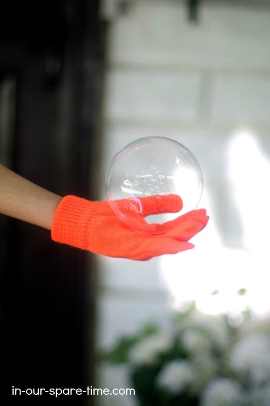 a girl's hand holding a large bubble