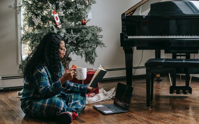 a woman reading a book in front of a Christmas tree