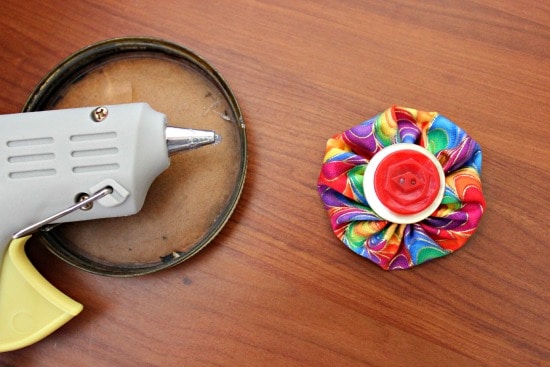 a glue gun next to colorful fabric round and buttons