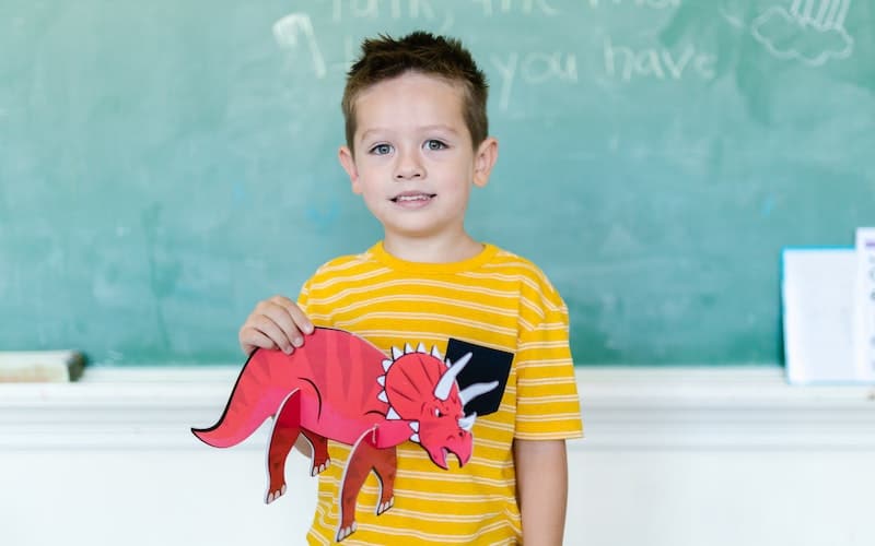 a boy holding a red dinosaur
