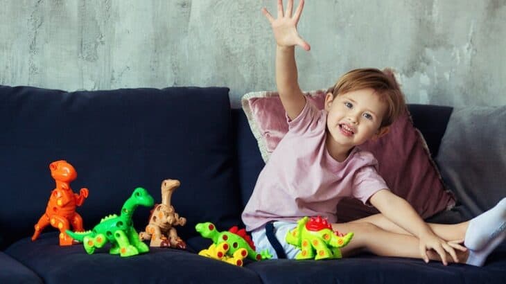 little girl playing with plastic dinosaurs