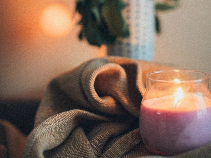 a pink candle on a brown blanket