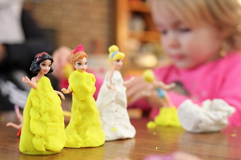 a little girl playing with princesses and playdough