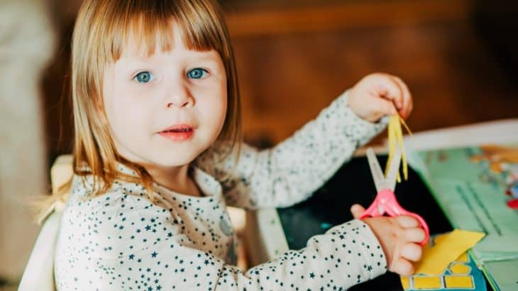 a little girl crafting with scissors and paper