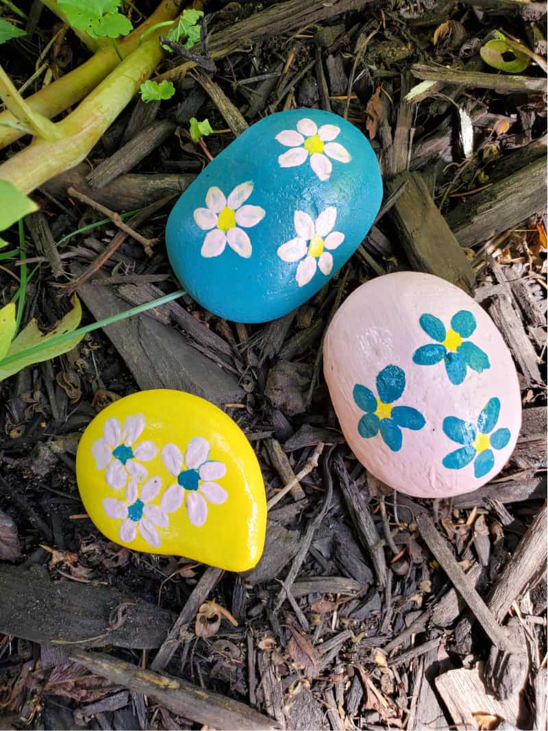 rocks painted with flowers on the ground