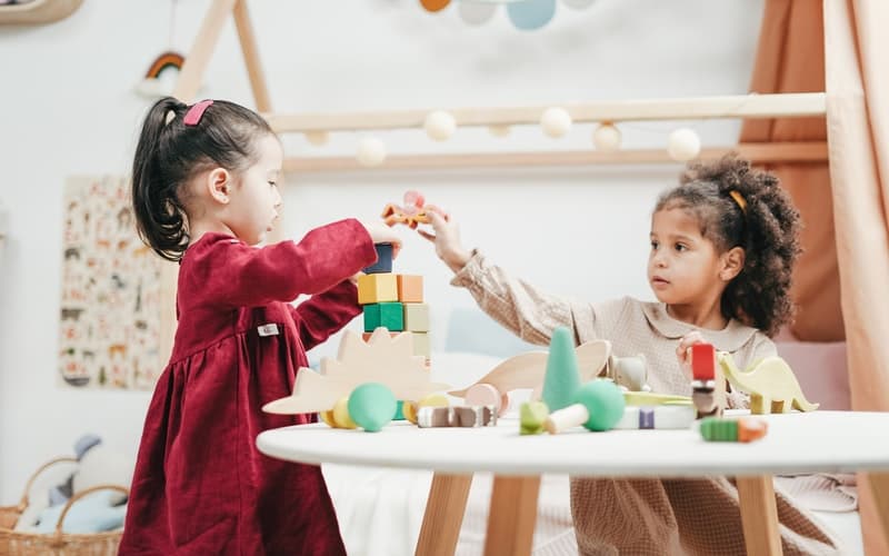 children playing with classic wooden toys on a wooden table