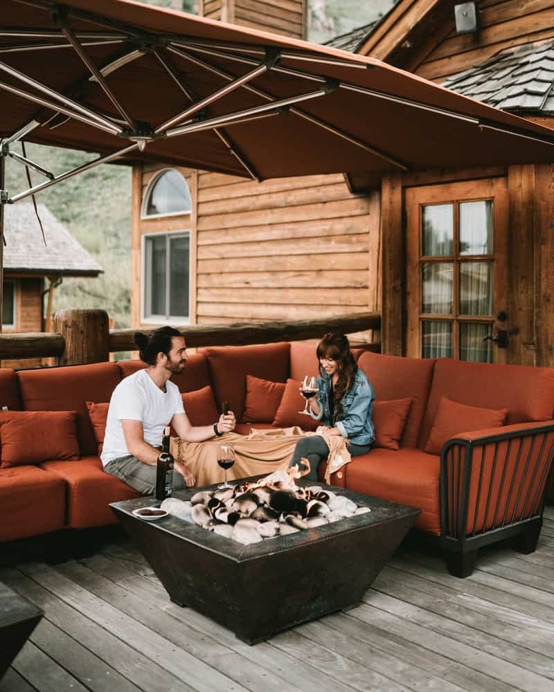 a couple sitting on their deck with furniture and a fire pit