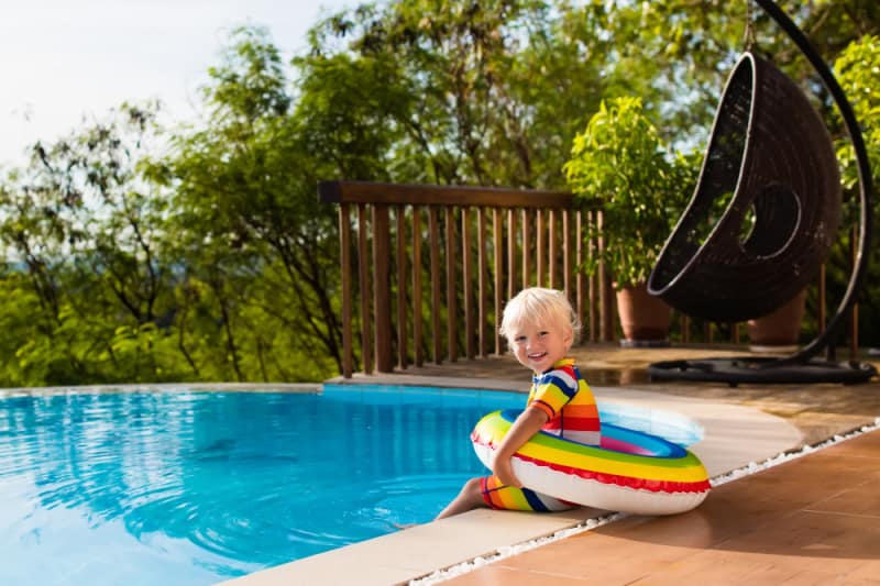 child sitting on a deck with a pool float