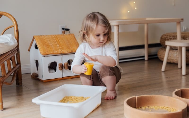 a toddler sorting pasta in bowls to play