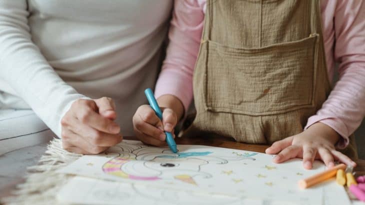 a child coloring with their mother