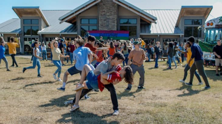 a group of teenagers dancing outside in front of a building