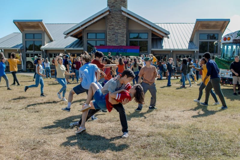 a group of teenagers dancing outside in front of a building