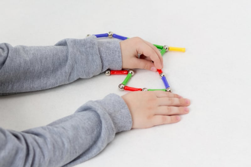 a boy playing with brightly colored magnets