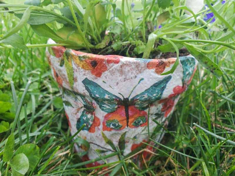a decoupaged flower pot in the grass