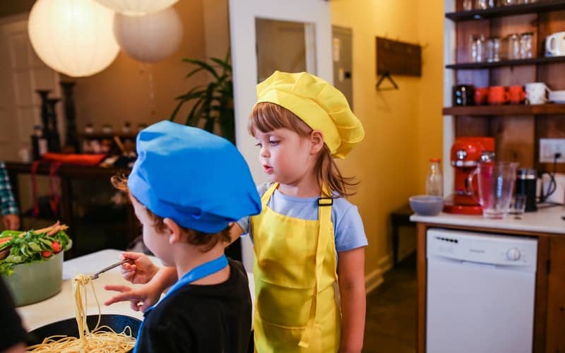 two children in aprons cooking together