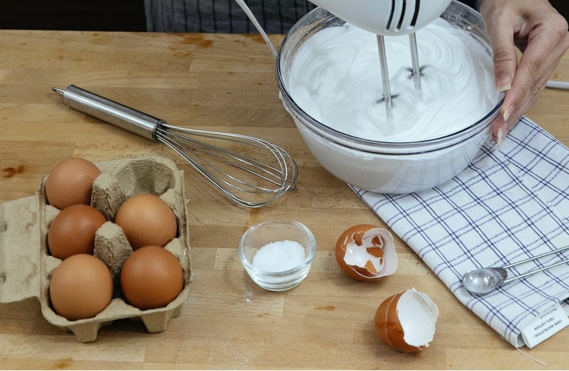 a woman using an electric beater to make cookies