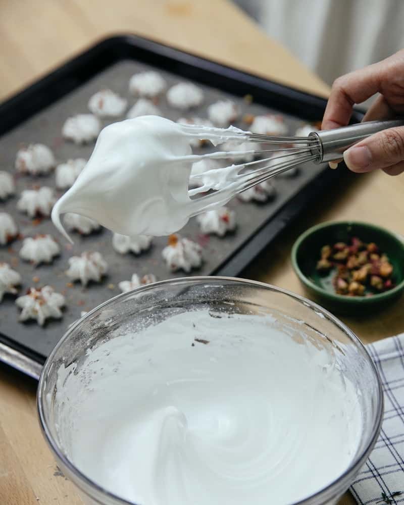 meringue on a whisk to show stiff peaks