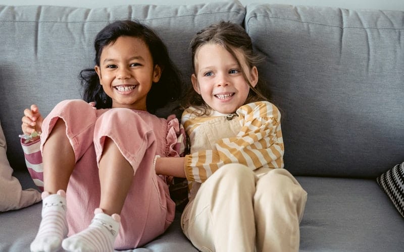 two young smiling girls sitting on the couch