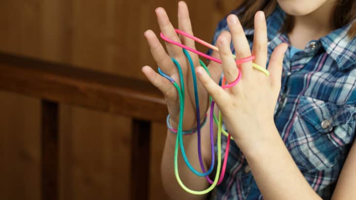 a girl playing cats cradle with string