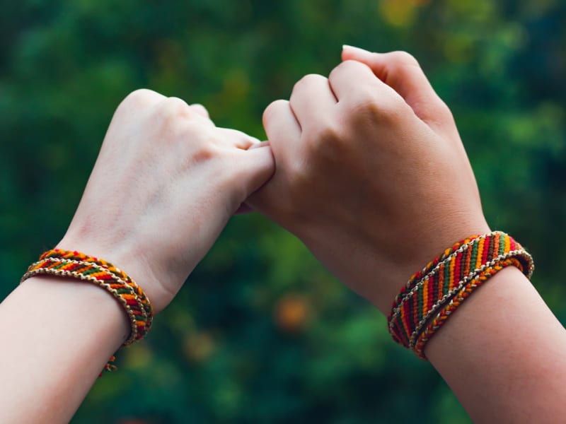 two children wearing friendship bracelets made with string