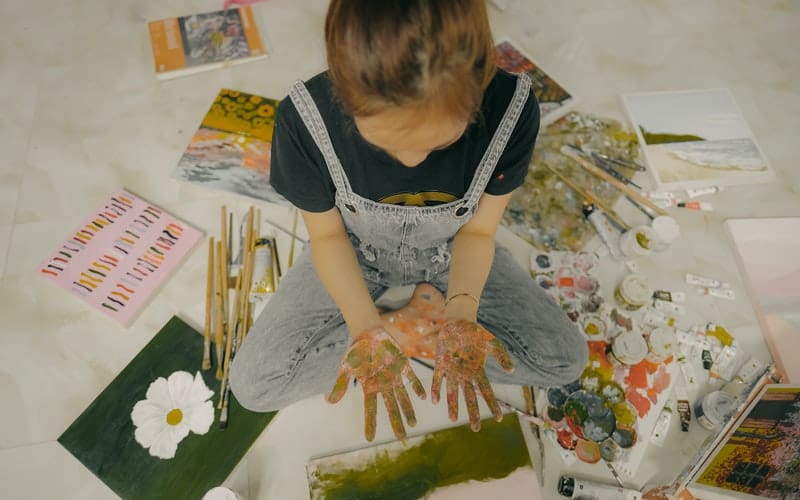 a girl painting with paint on her hands