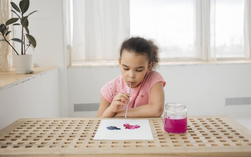 a girl sitting at a desk with art supplies