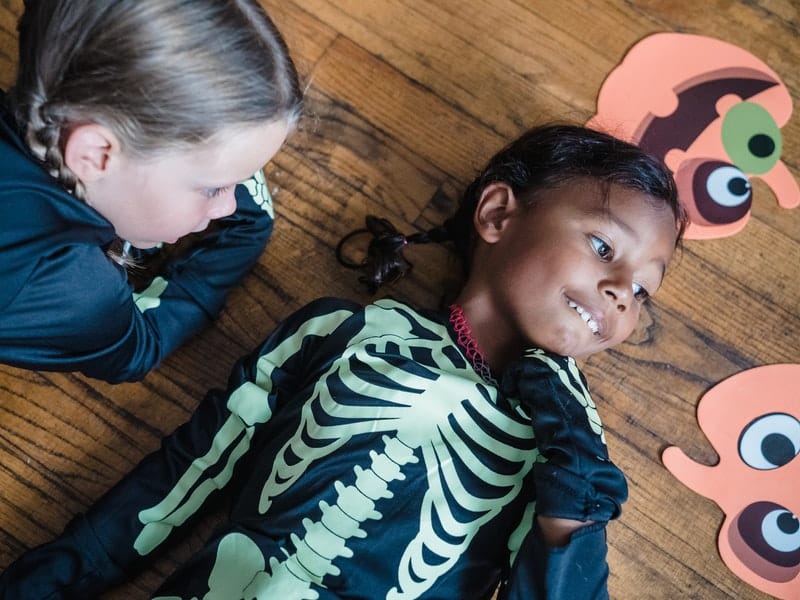two children laying on the ground in skeleton costumes