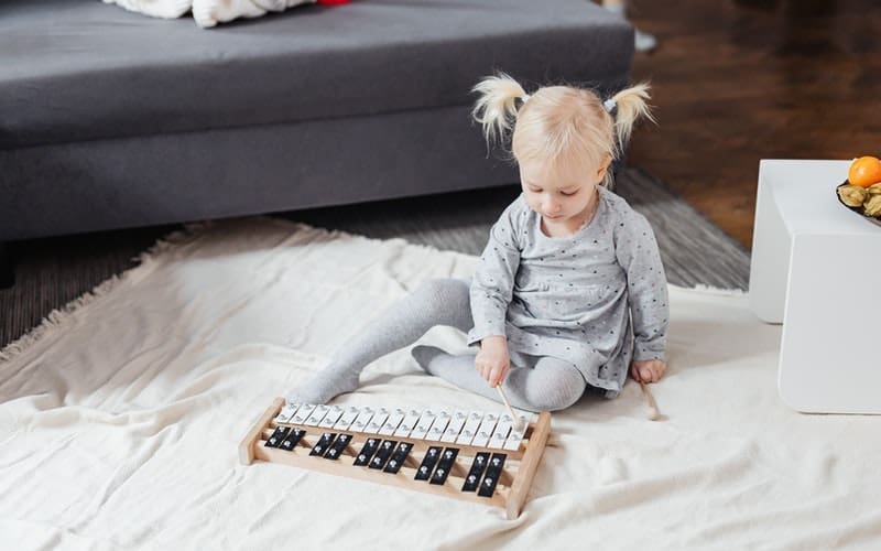 a young child playing with a xylophone on the floor