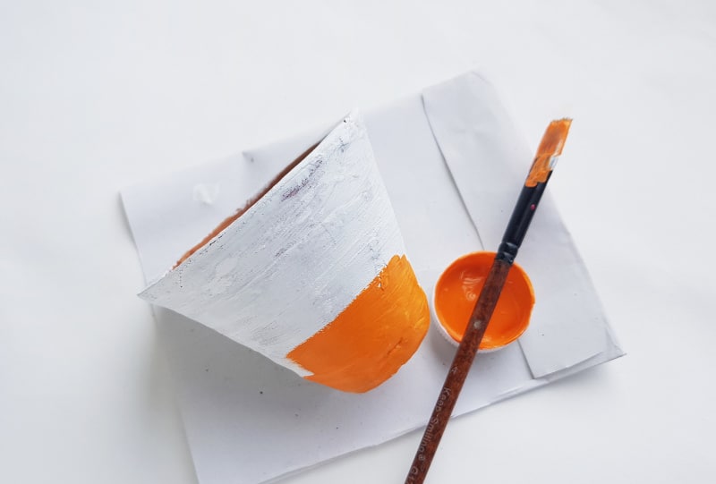 a partly painted white and orange pot