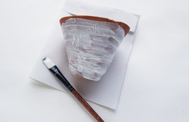 painting a flower pot white with a brush