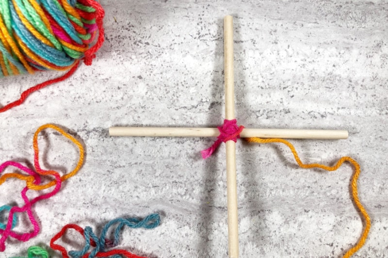 tying two craft sticks together with yarn