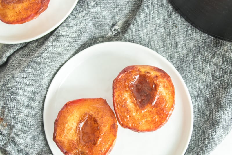 two cooked peach halves on a white plate