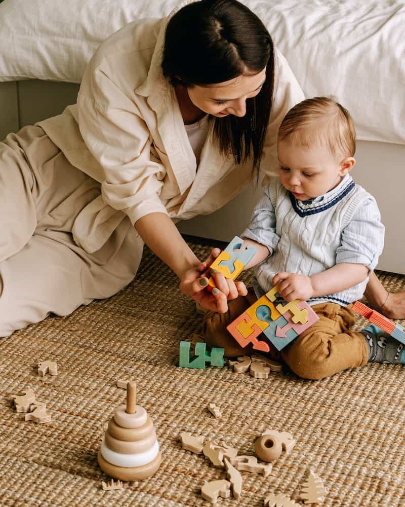 a mother and young child doing a wooden puzzle