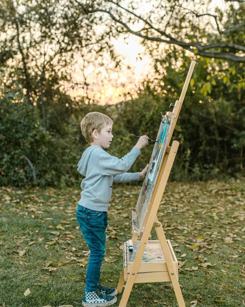 an older child painting on an art easel