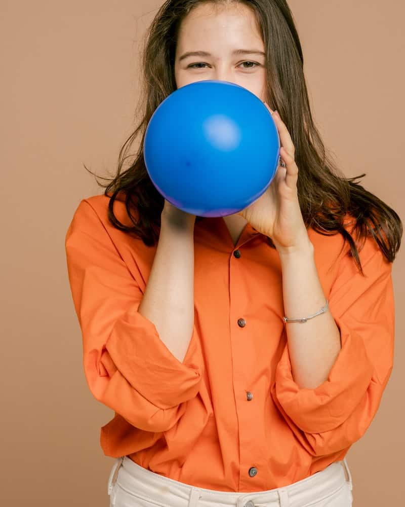 a woman blowing up a blue balloon