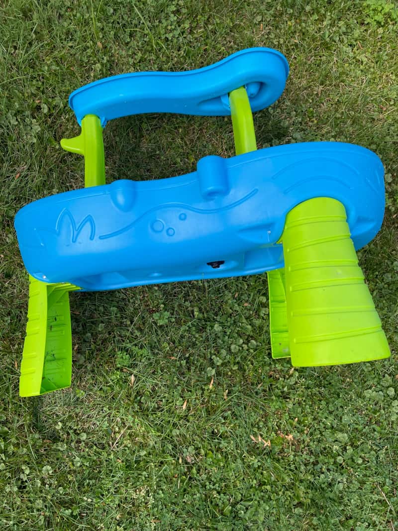 a blue and green children's toy in the grass