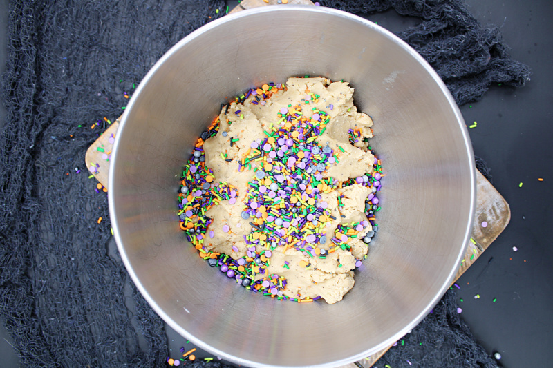 a metal mixing bowl with cookie dough and sprinkles