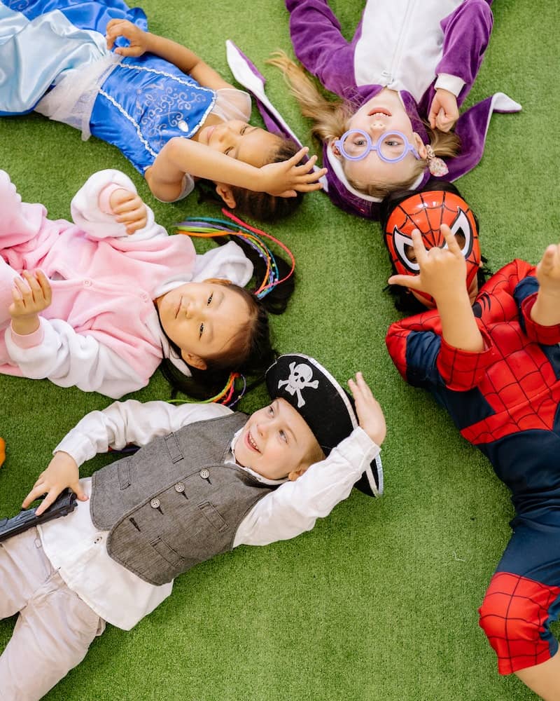 children wearing costumes lying on the ground