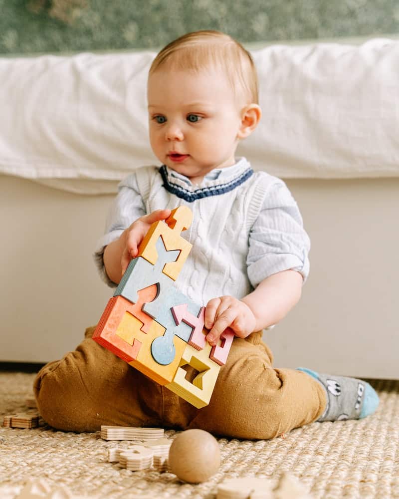 a boy playing with a wooden puzzle