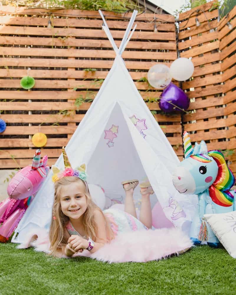 girl sitting in a tee pee with unicorn toys
