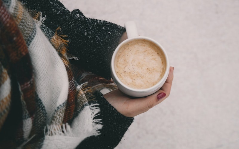 woman holding a cup of coffee standing in the snow