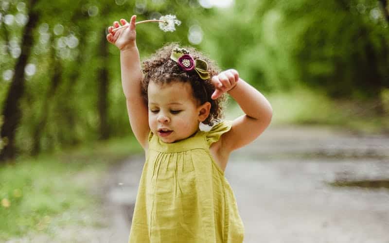 toddler holding a dandelion outside