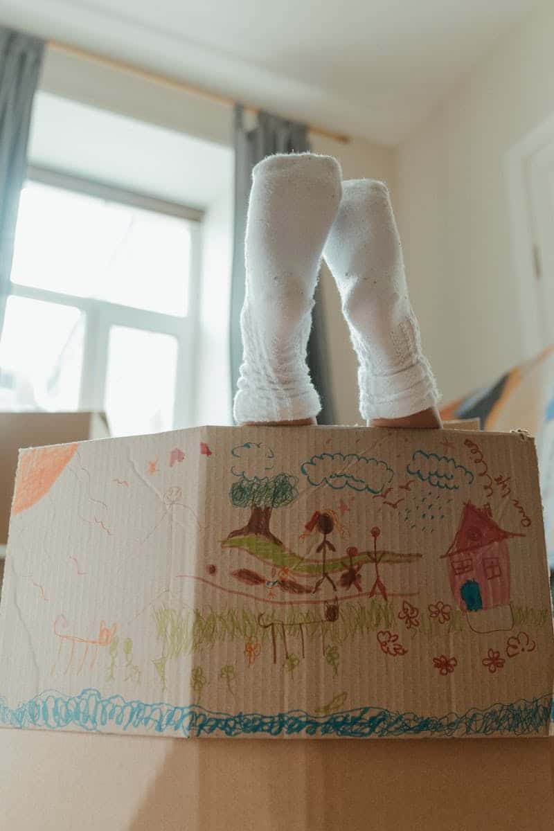 child hiding in a decorated cardboard box
