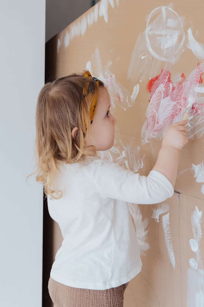 girl painting a cardboard box fort