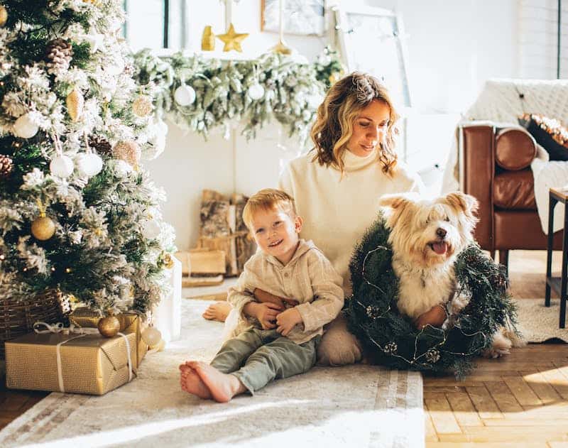 woman sitting near the tree with presents wrapped from this gift guide